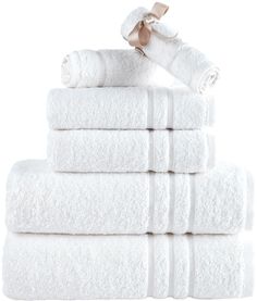 white towels stacked on top of each other in front of a white background with a gold ribbon