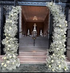 an entrance to a building decorated with white flowers and greenery in front of it