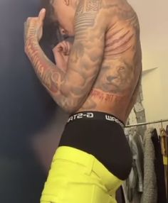 a man with tattoos on his back and yellow shorts