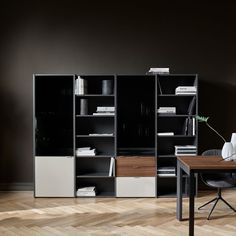 a black and white bookcase in an office with wooden flooring next to a desk