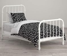 a white metal bed with black and white sheets