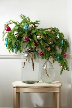 two vases with christmas ornaments on top of a table