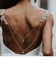 the back of a woman wearing a white dress with gold chains and flowers on it