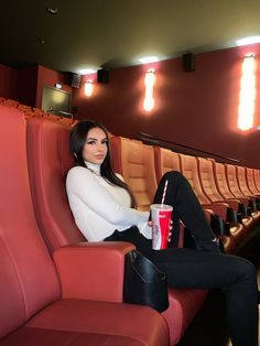 a woman sitting on a red chair with a drink in her hand