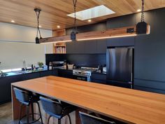 a kitchen with black cabinets and wooden counter tops, along with bar stools in front of the island