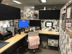 an office cubicle with two computer screens on the desk