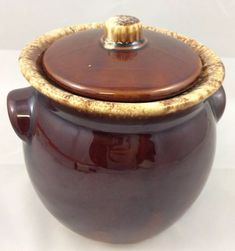 a large brown pot with a lid on it's side sitting on a white surface