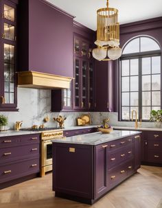 a kitchen with purple cabinets, gold accents and a chandelier hanging from the ceiling