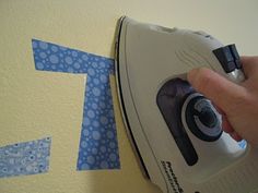 someone is using an iron to cut out the letters on the wall with blue tape