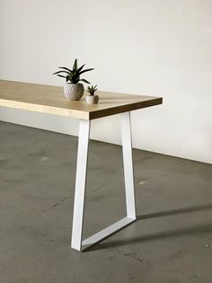 a wooden table with white legs and a potted plant sitting on top of it