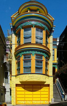 a tall yellow building with an arched window and balconies on the top floor