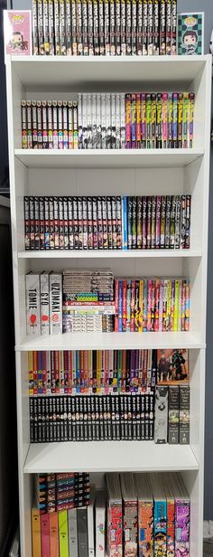 a white book shelf filled with lots of books and video game controllers on top of it