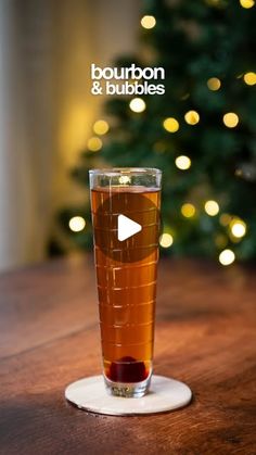 a glass filled with liquid sitting on top of a table next to a christmas tree