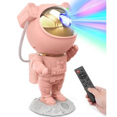 a person holding a remote control in front of a pink toy with a light on it