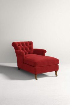 a red chair sitting on top of a white floor in front of a gray wall