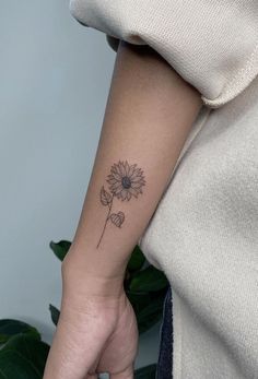 a woman's arm with a flower tattoo on the left side of her arm