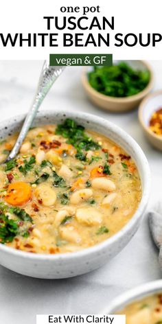 a bowl of white bean soup with carrots and spinach in it, on a table