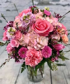 a vase filled with pink flowers on top of a wooden table