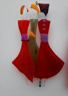 two red dresses are hanging on the wall next to each other and one is wearing an orange dress