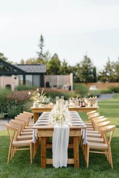 an outdoor table set with white linens and wooden chairs