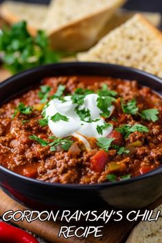 a black bowl filled with chili and sour cream