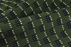 green and white patterned fabric with small black dots on the top, in front of a dark background