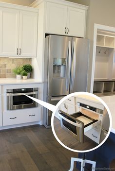 an open drawer in the middle of a kitchen with white cabinets and stainless steel appliances