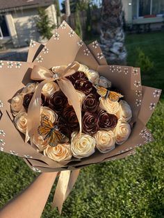 a person holding a bouquet of roses in their hand with butterflies on it and grass behind them