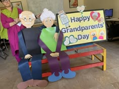 two women standing next to a sign that says happy grandparents day with paper cutouts on it