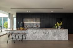 a kitchen with marble counter tops and stools in front of an island that has plants on it