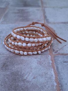 This Freshwater Pearl and Leather bracelet is the perfect combination of elegance and contemporary style. The bracelet wraps around the wrist 5 times and features beautiful cultured pearls and genuine leather. It's the perfect accessory to add a touch of sophistication to any outfit. This pearl wrap bracelet is a versatile accessory that can be dressed up or down. Choose from natural tan leather or dark brown leather. Adjustable sizing with button closure allows for a comfortable and secure fit Elegant Adjustable Brown Pearl Bracelet, Elegant Adjustable Hand Wrapped Pearl Bracelet, Elegant Brown Hand Wrapped Leather Bracelet, Adjustable Pearl Bracelets, Adjustable Cream Pearl Bracelets, Adjustable Cream Pearl Bracelet, Handmade Elegant Leather Bracelet, Elegant Multi-strand Adjustable Wrap Bracelet, Elegant Beaded Leather Bracelet Gift