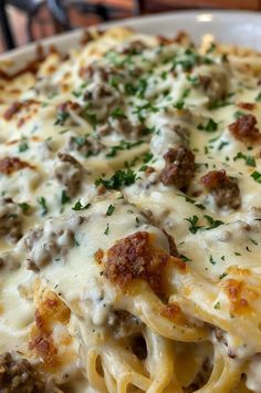 a white plate topped with pasta covered in meat and cheese