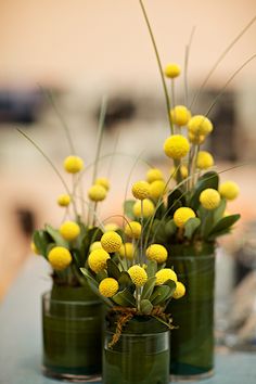 three green vases with yellow flowers in them