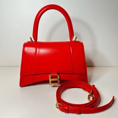 Condition : New With Box And Dustbag Size: Length: 9 In Height: 5.5 In Width: 4 In Drop: 3.5 In Drop: 13 In Description: This Is An Authentic Balenciaga Shiny Box Calfskin Small Hourglass Top Handle Bag In Bright Red. This Stylish And Structured Handbag Is Crafted Of Smooth Calfskin Leather. The Bag Features A Sturdy Leather Top Handle With Aged Goldlinks, A Prominent B Logo On The Front Flap, And An Optional, Adjustable Shoulder Strap. The Front Flap Opens With A Magnetic Snap Closure To A Smoo Evening Double Handle Box Bag With Original Box, High-end Red Shoulder Bag With Double Handle, High-end Red Satchel Box Bag, Red Shoulder Box Bag With Dust Bag, Red Shoulder Bag With Dust Bag, High-end Red Box Bag For Shopping, Luxury Red Handheld Box Bag, Designer Red Satchel Box Bag, Designer Red Rectangular Shoulder Bag