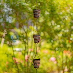 three pots hanging from a wire in front of trees