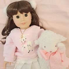 a doll and a white teddy bear sitting next to each other on a pink background