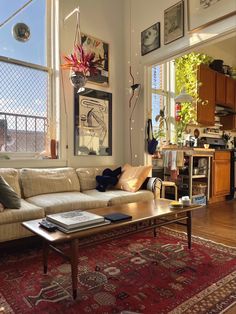 a living room filled with furniture next to a window covered in pictures and art on the walls