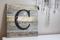 a wooden sign with the letter c on it and beads hanging from the wall behind it