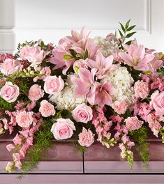 pink and white flowers are arranged on the top of a piano