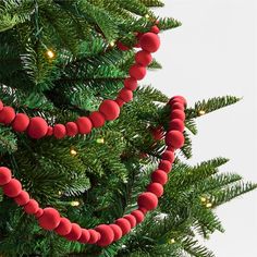 a close up of a christmas tree with red balls hanging from it's branches