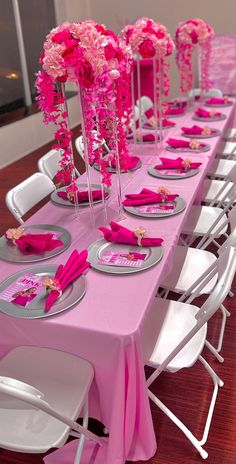 the table is set with pink flowers and plates