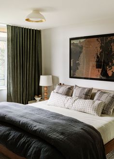 a bedroom with a large bed and green drapes on the window sill above it