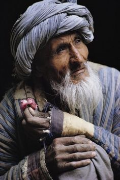 an old man wearing a turban and holding something in his hands