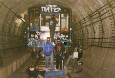 some people are standing in the middle of a train tunnel with graffiti on its walls