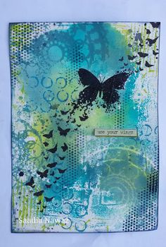 an art journal with blue and green designs on the pages, including a black butterfly