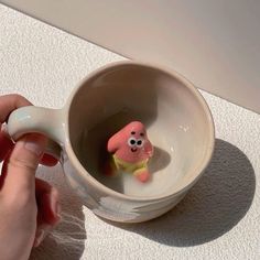 a hand holding a cup with a small toy in the bottom and a tiny figure inside