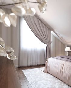 a large bed sitting under a window next to a white rug on top of a hard wood floor