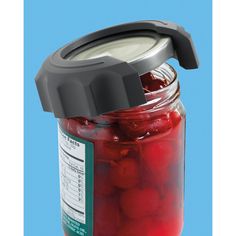 a jar filled with cherries sitting on top of a blue table next to a black lid