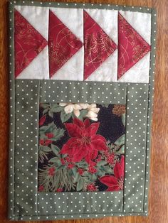 a close up of a piece of cloth on a wooden table with red and white flowers