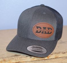 "This DAD hat is a great gift for Father's day or it can be an announcement of pregnancy.  This is a great way to show off that your a dad and you can proudly show the names of your children.  Buy this for yourself of for that special dad in your life.   To order a hat just select the hat color you would like and in the personalization section of the order just include the name and number you would like on the hat.  If you are looking for customization options not shown in the listing please contact me.  I am happy to help.   You have the option to have this patch placed on the center of the hat or to the side as shown in the image.    The hat is the classic Yupoong 6606 Trucker Hat Material:  - 65% polyester, 35% cotton Feature:  - 6-panel, structured, hard buckram backed front panels  - Day Name, Leather Patch Hat, Custom Patch, Patch Hat, Hat Custom, Custom Patches, Custom Hats, Dad Hat, Leather Patches